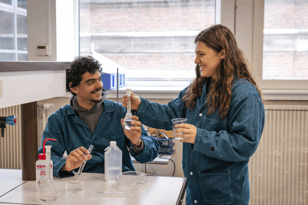 deux étudiants échangent un bécher dans un laboratoire de chimie