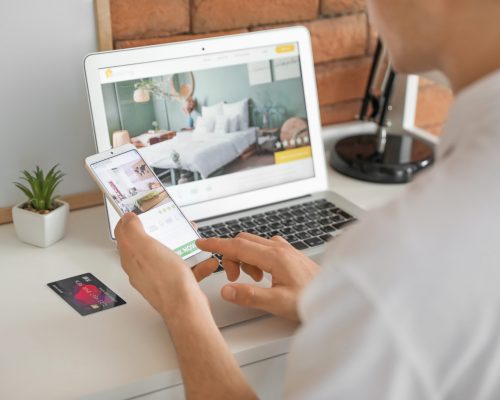 Man with mobile phone booking room in hotel online at home Man with mobile phone booking room in hotel online at home